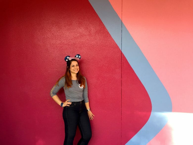 A Thais do VPD posando na Bubblegum Wall do Epcot, a parede vermelha, azul e rosa 