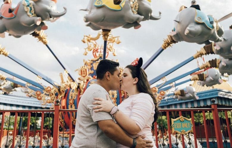 Foto da Thais beijando o namorado em frente à atração do Dumbo, na Fantasyland 
