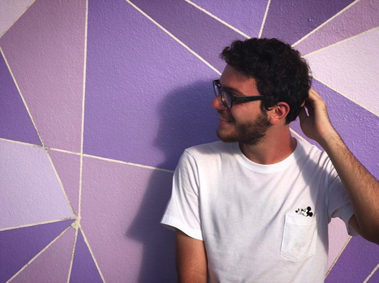 Foto do Marcelo, da equipe do VPD, na parede roxa da Tomorrowland
