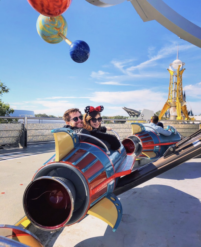 A leitora Bia com o namorado no carrinho do Astro Orbiter, na Tomorrowland, olhando para trás. 