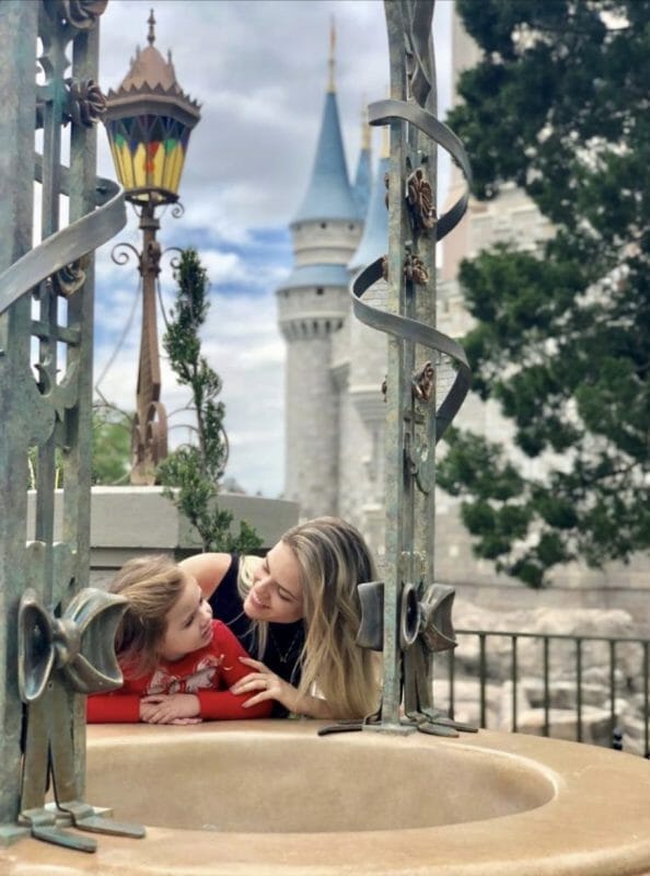 A leitora Flavia com a filha posando na fonte do castelo da Cinderela 