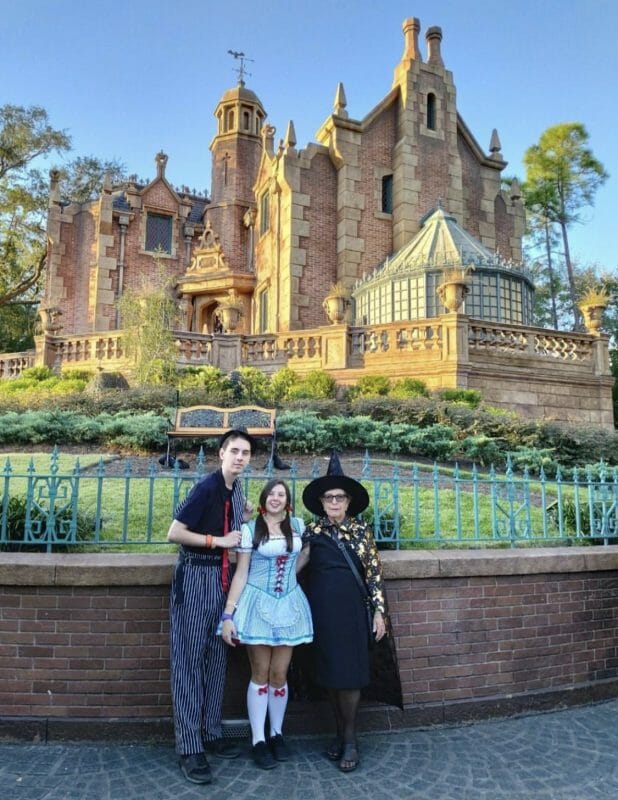 Foto da leitora Aline com a família fantasiados no Halloween, posando em frente à Haunted Mansion