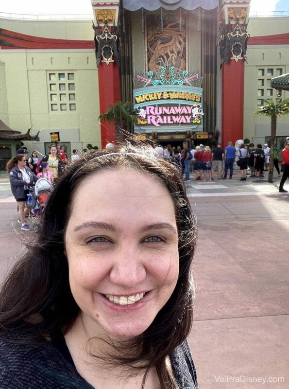 Foto da Renata sorrindo em frente à Mickey & Minnie's Runaway Railway durante o dia, no Hollywood Studios