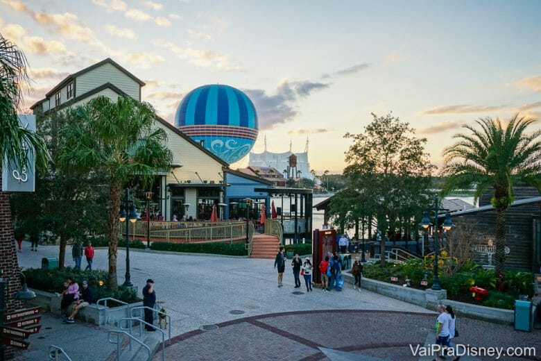 Foto de um fim de tarde em Disney Springs, mostrando o balão da Disney, as árvores e visitantes passeando. 