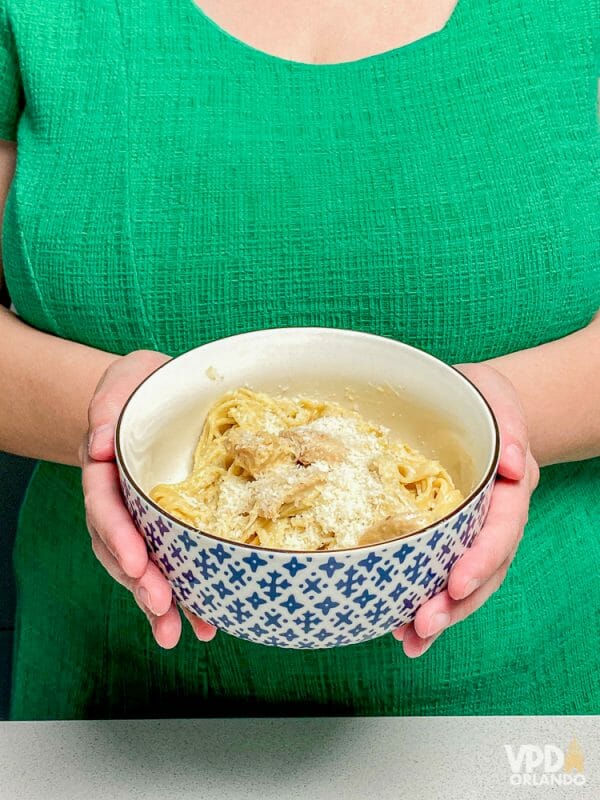 Foto de duas mãos segurando uma tigela com macarrão 