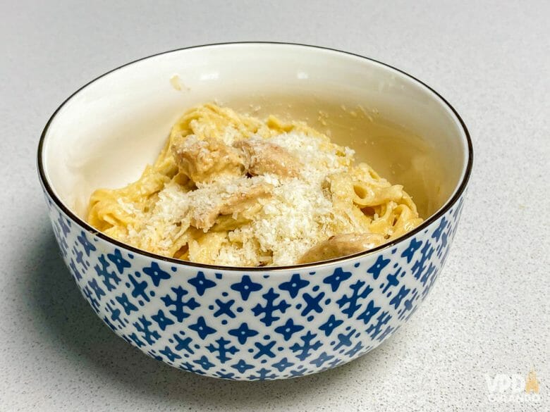 Foto do fettuccine já pronto, com queijo ralado em cima, em uma tigela azul e branca 