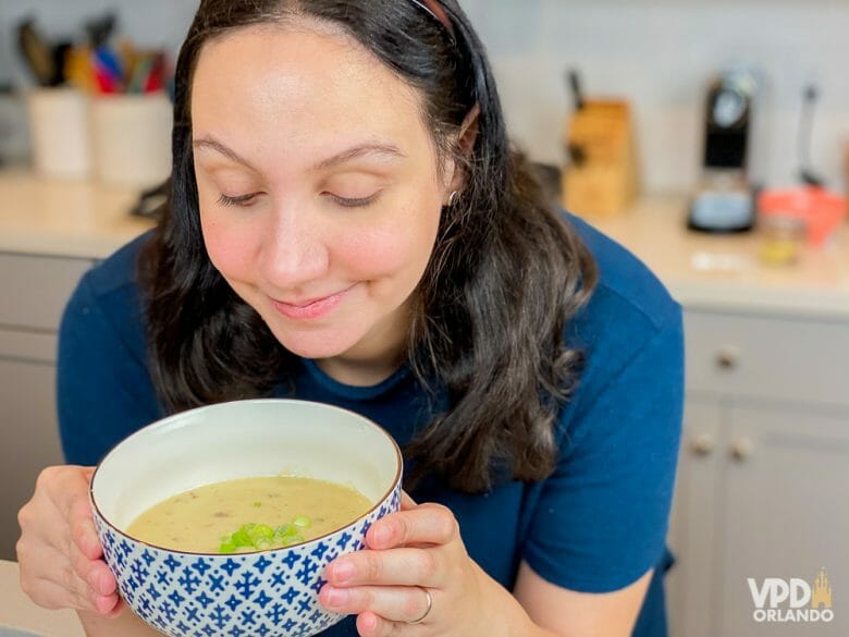 Foto da Renata com uma tigela azul e branca com a sopa de cheddar do Le Cellier, com um pouco de cebolinha picada por cima 