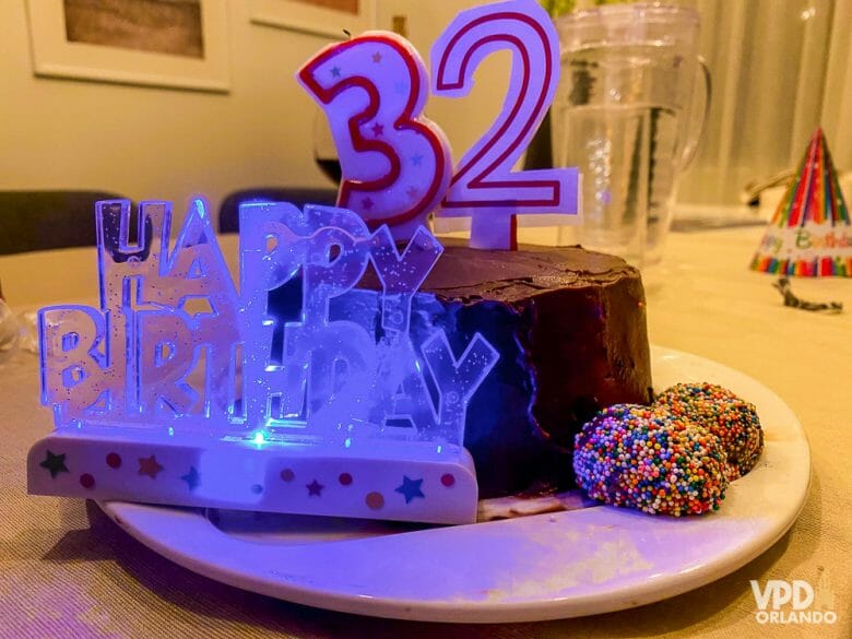 Foto do bolo de aniversário da Renata, com as velas indicando 32 anos e uma plaquinha iluminada que diz "Happy Birthday", enquanto ela estava em quarentena em Orlando 