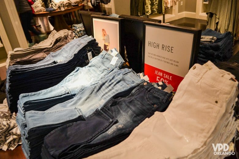 Se a roupa não servir, é fácil de fazer a troca! Foto de calças jeans à venda em uma loja, com uma placa que diz "high rise" (cintura alta) 