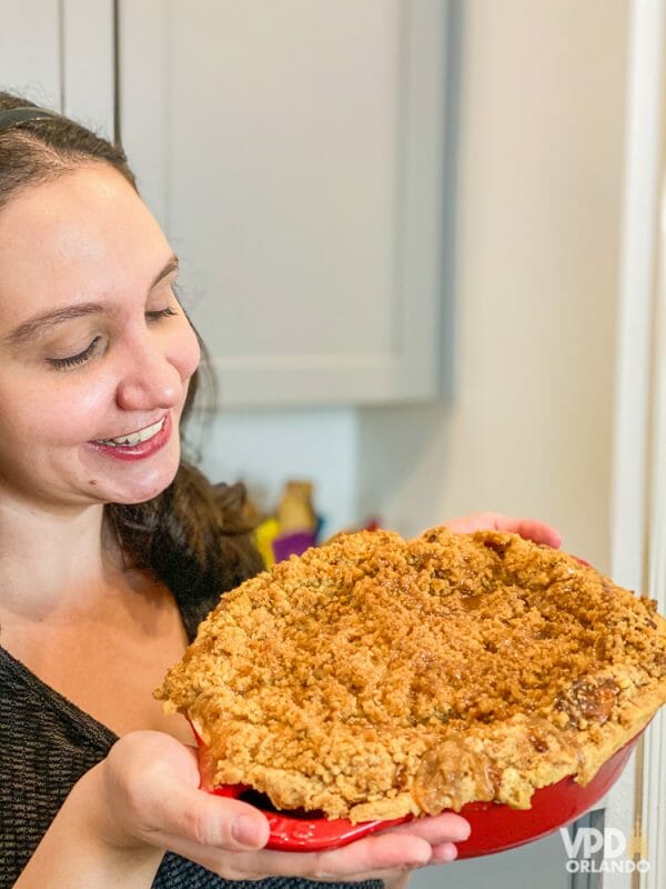 Sim, eu olho com amor pra torta, e é amor verdadeiro, de mais de 10 anos! Foto da Renata segurando a torta já pronta em uma vasilha vermelha, olhando para ela e sorrindo 