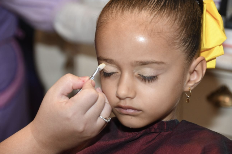 Foto da filha do leitor Fabiano com um laço amarelo no cabelo, sendo maquiada no Bibbidi Bobbidi Boutique