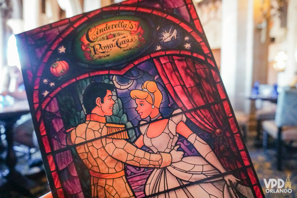 Foto da capa do cardápio do restaurante Cinderella's Royal Table, que tem a imagem de um vitral em que a Cinderela está dançando com o príncipe.