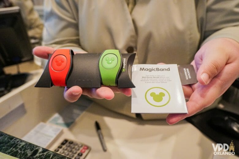 Pessoa segurando duas MagicBands, uma vermelha e uma verde. Essa foi uma das mudanças da Disney em 2021, elas não são mais gratuitas para hóspedes.