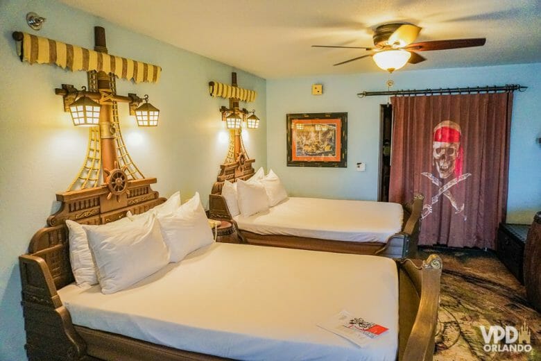 Muitos hotéis oferecem cancelamento gratuito, super importante nesse momento de incertezas! Foto do quarto pirata do hotel Caribbean Beach. A cama é um barco, e a cortina mostra uma caveira pirata. 