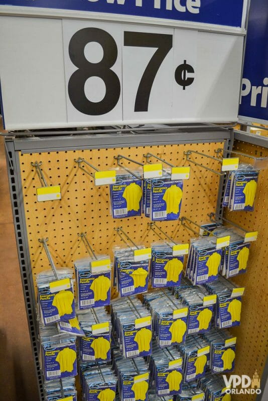 Foto das capas de chuva vendidas no Walmart, com o preço em uma placa acima (87 centavos de dólar) 
