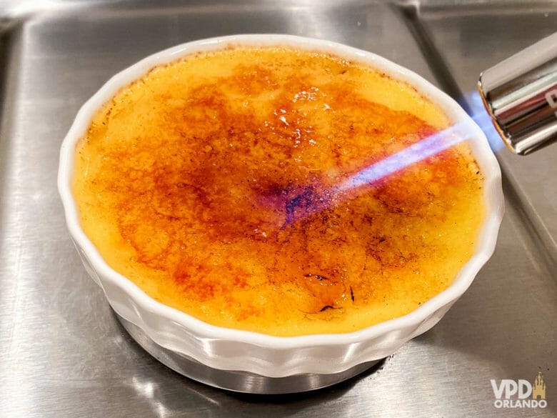 Foto da cobertura de açúcar do crème brûlée sendo caramelizada pelo maçarico 