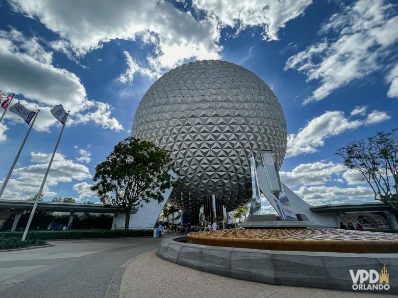 A famosa "bola do Epcot". Foto da "bola" que é símbolo do Epcot, onde fica a atração Spaceship Earth, com o céu azul ao fundo e alguns visitantes passando ao redor. 