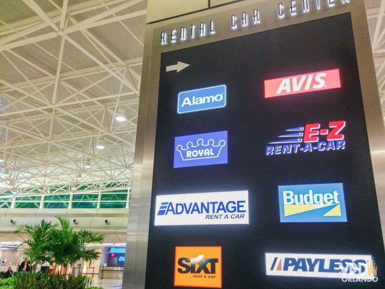 Atenção na hora de escolher a sua locadora. Veja a política de cobrança de pedágios automáticas praticada. Foto da placa do aeroporto indicando o centro de aluguel de carro e as diversas locadoras disponíveis 