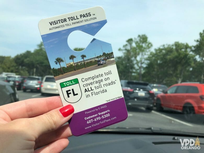 Visitor Toll Pass: nova opção simples e econômica de pagar pedágios na Flórida. Foto de uma mão segurando o Visitor Toll Pass para ser colocado no carro. 