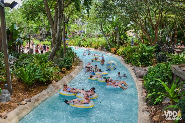 Imagem do rio de corredeira no parque aquático Typhoon Lagoon. Os visitantes estão flutuando no rio sobre boias, e há árvores ao redor.
