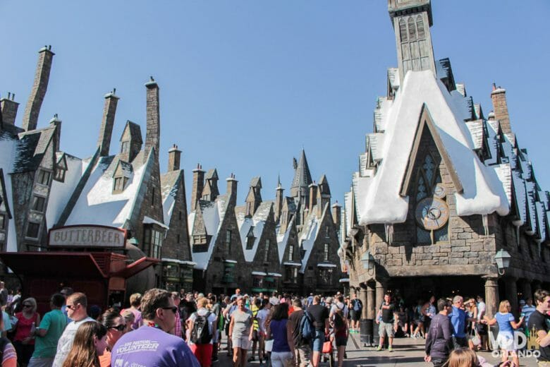 Foto de Hogsmeade, no Islands of Adventure, um dos parques da Universal, com as construções cobertas de neve falsa e o céu azul ao fundo. 