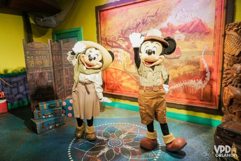 Foto do Mickey e da Minnie com roupa de safári, acenando para a foto, durante um encontro com visitantes. 