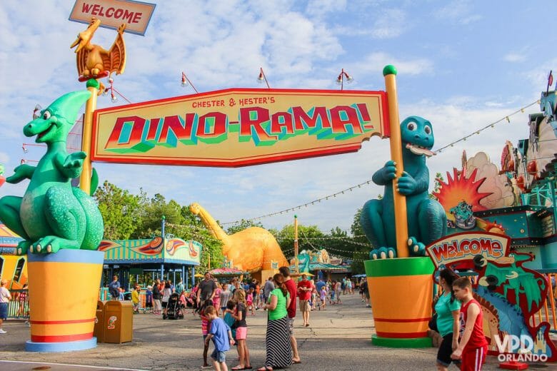 Foto de uma placa que diz "Dino-Rama", segurada por dois dinossauros, na área Dinoland U.S.A 