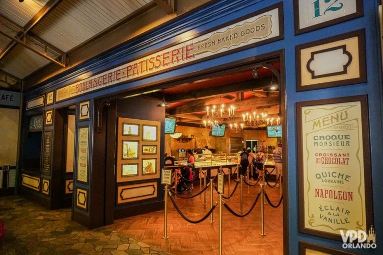 A Patisserie no fundo do pavilhão é cheia de opções gostosas. Foto da Patisserie no pavilhão da França do Epcot, com o menu de itens franceses na parede ao lado da porta. 