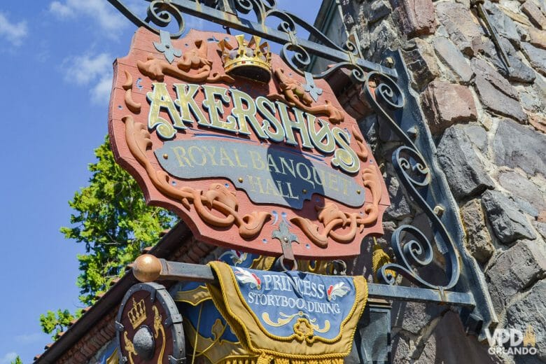 O Akershus é uma opção de refeição com as princesas no Epcot. Foto da placa na entrada do Akershus Royal Banquet Hall, com letras medievais e uma coroa sobre o título. 