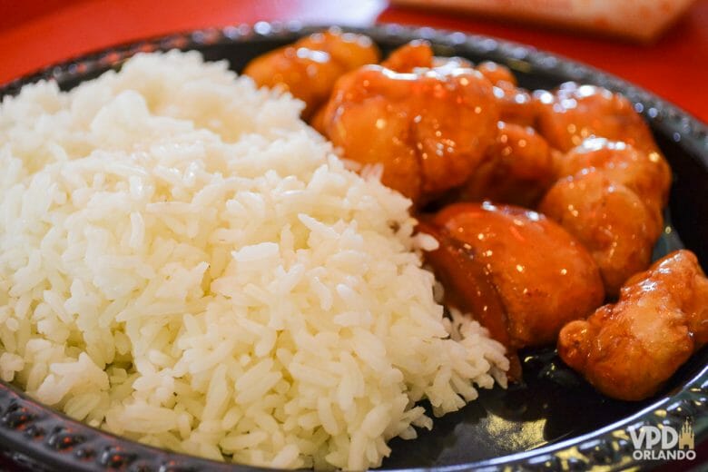 O frango empanado ao molho de laranja do pavilhão da China é um dos meus preferidos no Epcot! Foto de um prato com frango empanado e arroz 