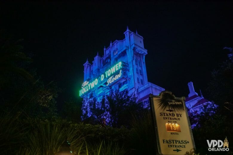 Imagem da atração Tower of Terror, no parque Hollywood Studios, à noite. Iluminada com luzes roxas e verdes.