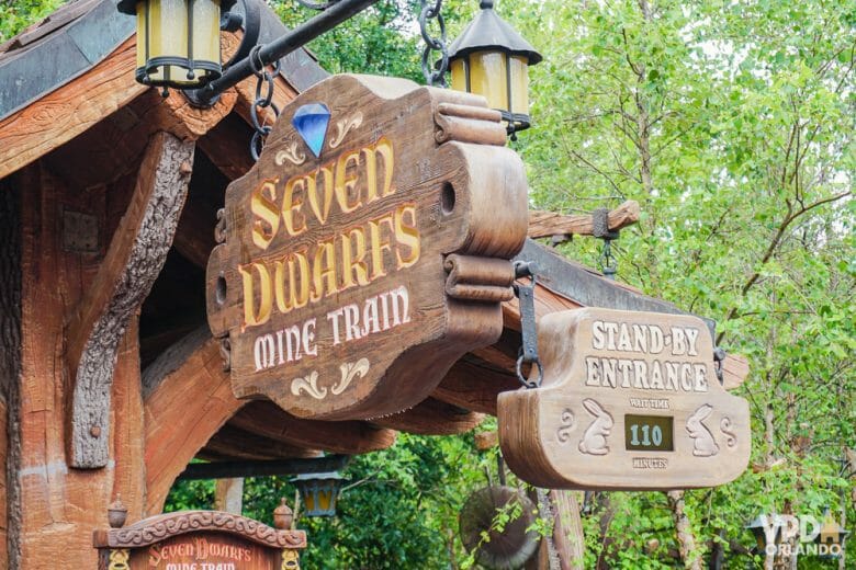 Foto da entrada da Seven Dwarfs Mine Train no Magic Kingdom. As placas de madeira exibem o nome da atração e "stand-by entrance" com o tempo de espera abaixo 