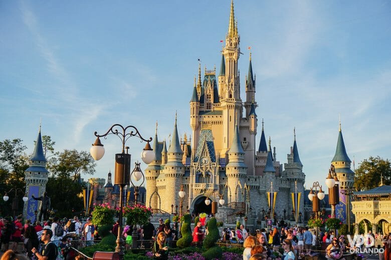 Imagem do Magic Kingdom em um dia de céu azul e movimentado, com o castelo da Cinderela ao fundo. 