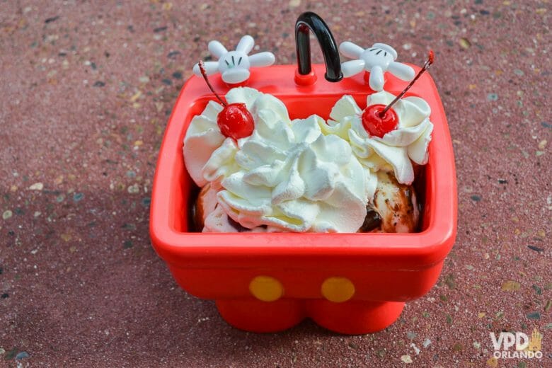 Foto do sundae do Mickey vendido no Magic Kingdom, num recipiente vermelho, com uma cobertura de chantilly e duas cerejas. 