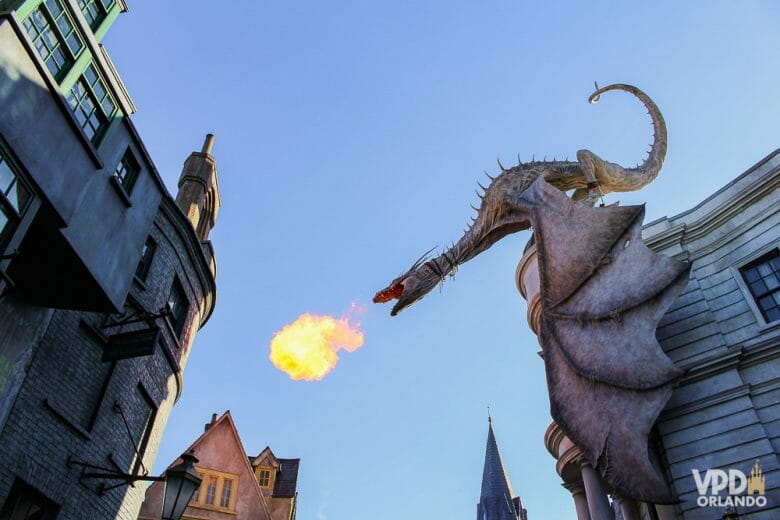 Foto no dragão em cima do prédio de Gringotts, no Beco Diagonal, com um céu claro ao fundo. Ele está cuspindo fogo. 