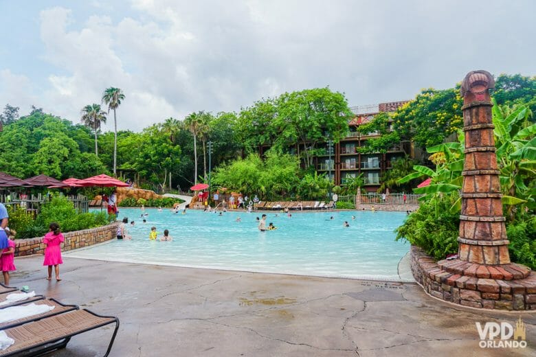 A piscina do Animal Kingdom Lodge é linda e gigante... Foto da piscina do Animal Kingdom Lodge, com o prédio do hotel ao fundo e um pilar decorativo em primeiro plano. 