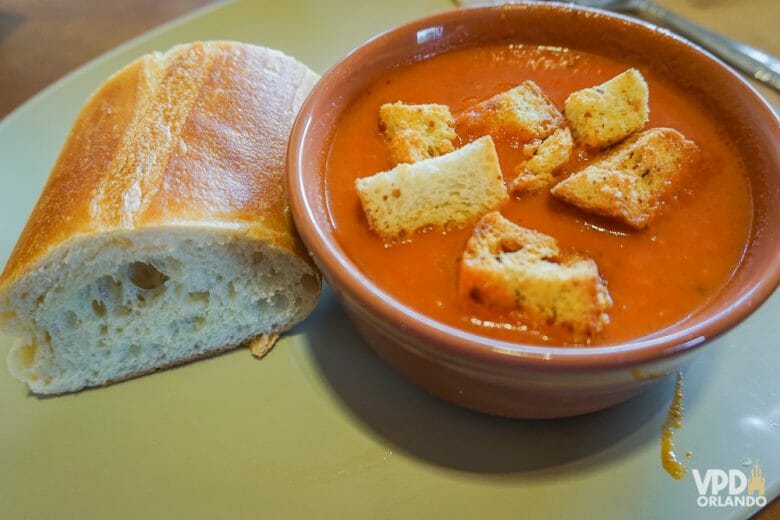 Sopinha de tomate da Panera Bread, acompanhada de um pedaço da baguete de pão francês. Foto do prato no Panera Bread, uma sopa de tomate com croutons e um pedaço de pão ao lado. 