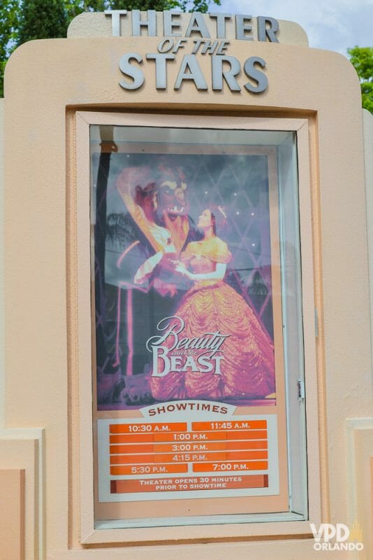 Foto do cartaz do show da Bela e a Fera no Hollywood Studios. Há uma imagem dos personagens e abaixo, os horários dos shows em um fundo laranja. 