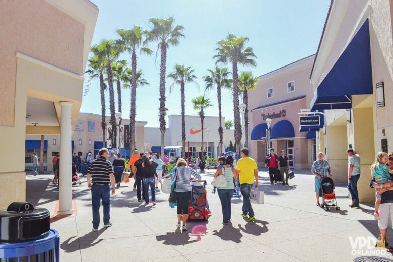 Até o mais apaixonado por parques acaba comprando um pouquinho e visitando os shoppings em Orlando, né? Foto da área aberta de um outlet, com visitantes passeando e o céu azul ao fundo 