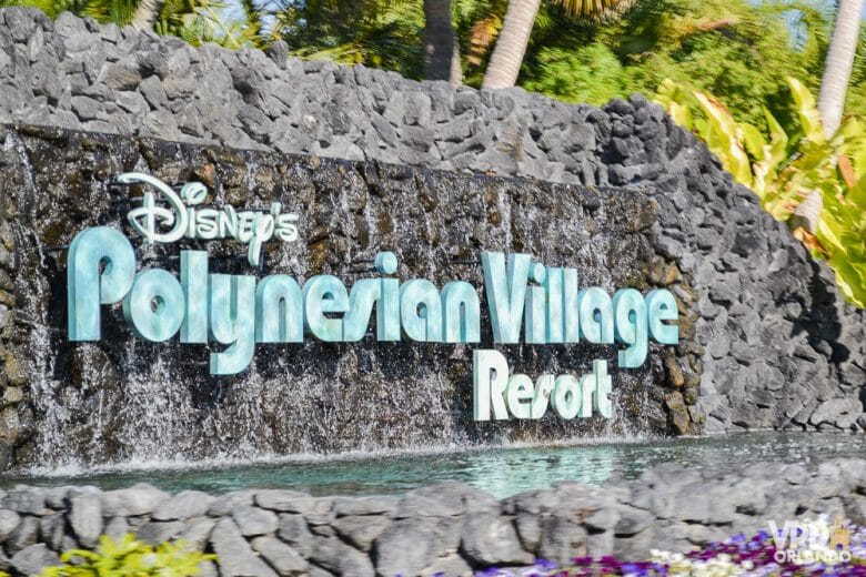 Foto da entrada do hotel Disney's Polynesian Village Resort. O fundo da placa é de pedra e as letras são azul-claras. 