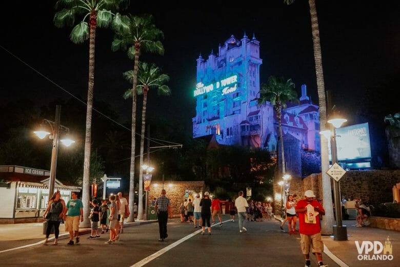 Imagem do Hollywood Studios à noite, com a Tower of Terror iluminada em azul ao fundo.