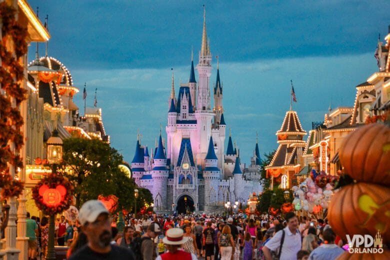 Foto da Main Street do Magic Kingdom, decorada com muitas abóboras. A rua está cheia e está anoitecendo. 