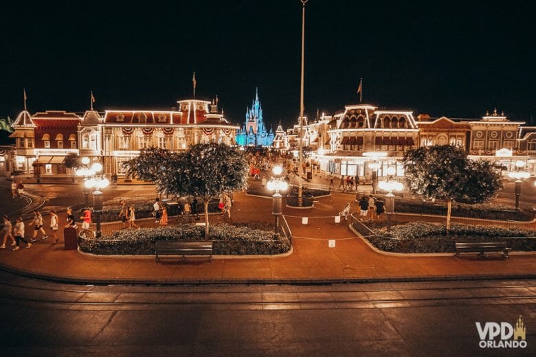 Imagem mostrando o início da Main Street no Magic Kingdom à noite. O parque está vazio, com algumas pessoas perto do castelo e outras saindo do parque.