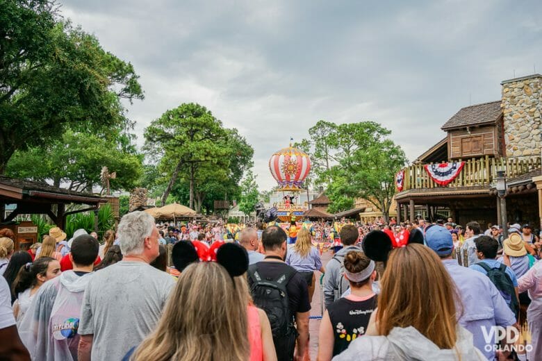 Imagem da Frontierland no Magic Kingdom, onde a parada da tarde está passando. Várias pessoas andam atrás do carro que leva o Mickey e a Minnie