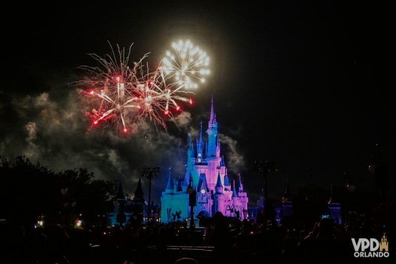 Castelo do Magic Kingdom à noite, iluminado de roxo e azul pelo show de fogos Happily Ever After, ainda sem data prevista para retorno em 2021.