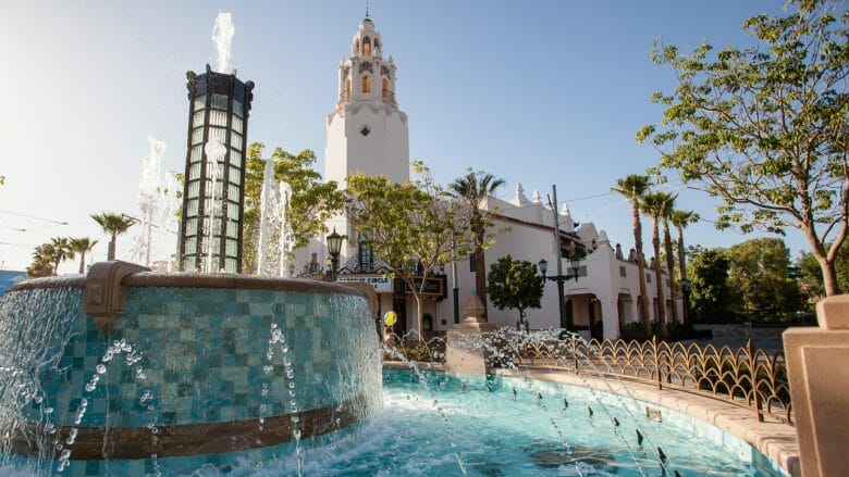 Imagem do Buena Vista Street, com uma fonte d'água e árvores ao fundo.