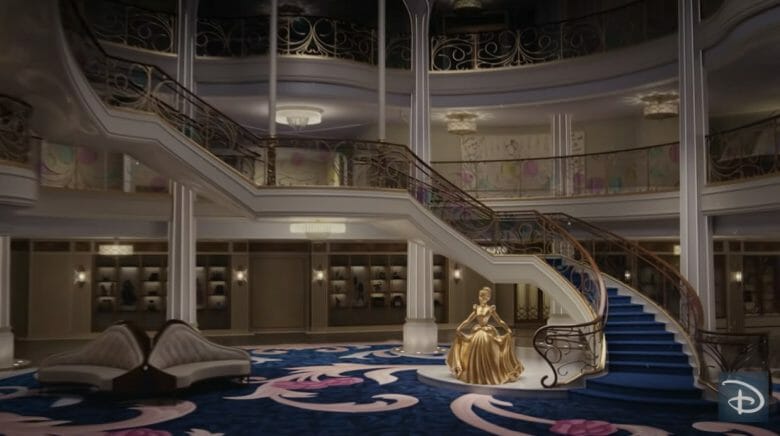 Imagem do novo navio Disney Wish, com estátua dourada da Cinderella ao lado da escadaria.