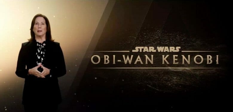 A imagem mostra uma mulher, Kathleen Kennedy, anunciando a série de Obi Wan Kenobi que vai chegar ao Disney Plus. Ela está em frente a uma tela com o nome da série.