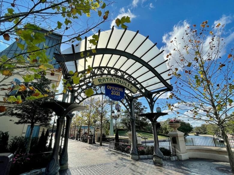 Imagem do arco de entrada da nova área do pavilhão, com árvores e uma placa escrito Ratatouille. A expansão do pavilhão da França no Epcot foi inaugurada na semana passada.