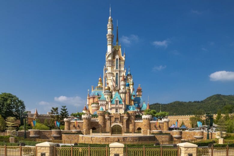 Novo castelo da hong Kong Disneyland em cor bege, com torres de diferentes cores como azul, amarelo e vermelho, e ao fundo o céu azul com poucas nuvens.